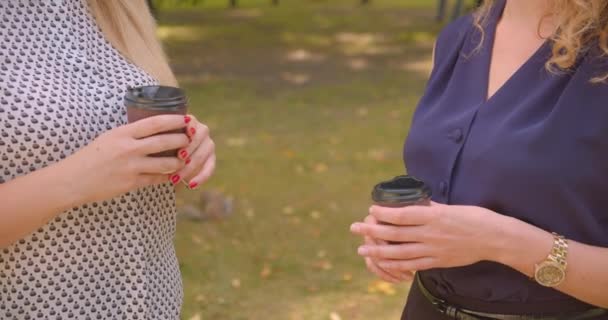 Retrato de cerca de dos manos femeninas sosteniendo café en el parque al aire libre — Vídeos de Stock