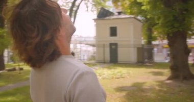 Parkta duran neşeli beyaz adam havada gezinen kameralı yakın çekim portre