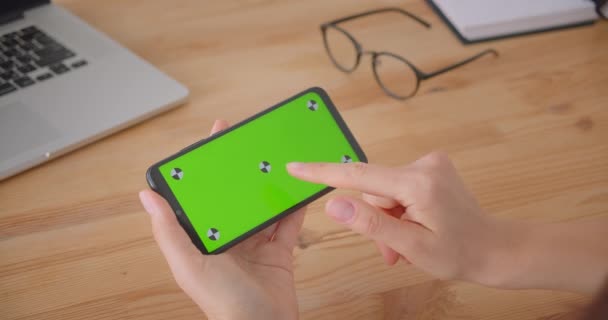 オフィス内の緑のクロマキー画面で携帯電話で広告を再生若い女性医師のクローズアップバックビューの肖像画 — ストック動画