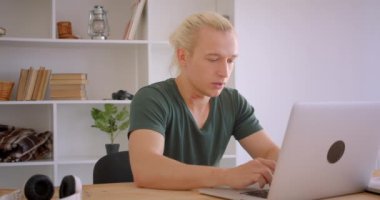 Ofiste kamera kapalı bakarak dizüstü bilgisayar kullanarak genç çekici sarışın hipster işadamı Closeup portre