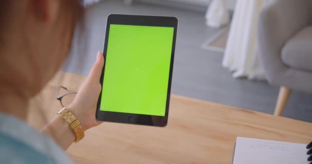 Closeup back view portrait of young caucasian female doctor using tablet with green screen indoors in office — Stock Video