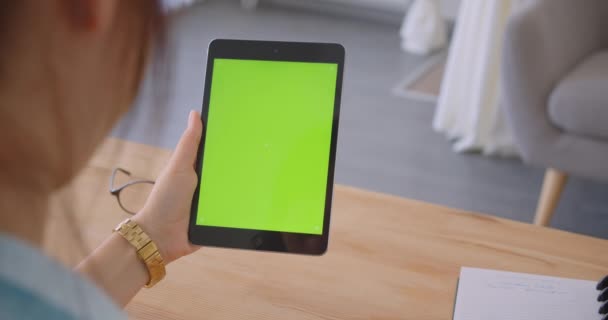 Closeup back view portrait of young caucasian female doctor using tablet with green chroma screen indoors in office — Stock Video