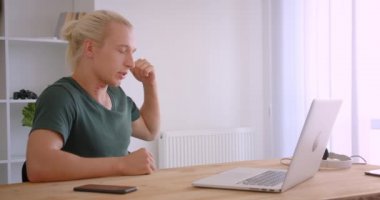 Ofiste kapalı masada oturan dizüstü bilgisayar da görüntülü arama olan genç çekici sarışın hipster işadamı Closeup portre