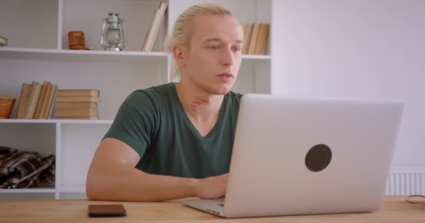 Close-up retrato de jovem bonito loira hipster empresário usando laptop dentro de casa no escritório — Vídeo de Stock