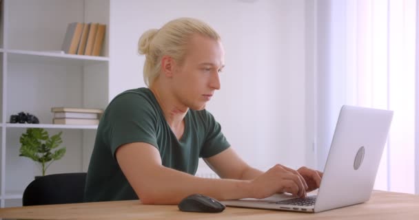 Closeup vista lateral retrato de jovem atraente loira hipster empresário usando laptop dentro de casa no escritório — Vídeo de Stock