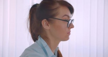 Ofiste kamera kapalı bakarak gözlük genç başarılı çekici kafkas kadın doktor Closeup yan görünüm portresi