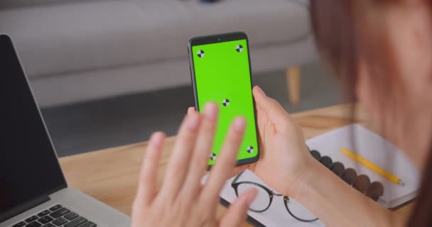 Gros plan vue de dos portrait de jeune main féminine en utilisant le téléphone avec écran chromatique vert clé à l'intérieur dans le bureau — Video