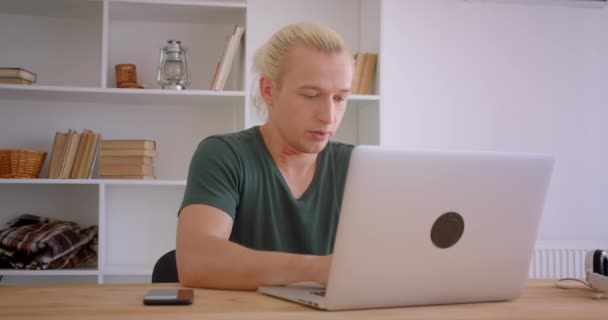 Close-up portret van jonge knappe blonde hipster zakenman werken op laptop binnenshuis in kantoor — Stockvideo