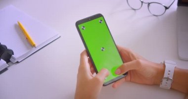 Ofis kapalı yeşil renk anahtar ekranı ile genç güzel kafkas iş kadınlarının el tutan telefon Closeup portre