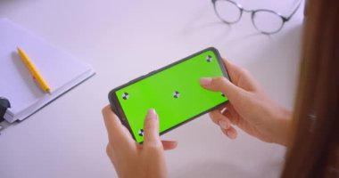 Ofis kapalı yeşil renk anahtar ekranı ile genç kafkas iş kadınlarının el tutan telefon Closeup portre