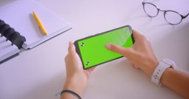 Genç kafkas iş kadınlarının kapalı ofiste yeşil renk anahtar ekranı ile el tutan telefon closeup portre masada ofis kapalı