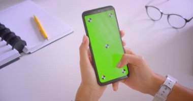 Masa başında ofis kapalı yeşil renk anahtar ekranı ile telefon kullanarak genç kafkas iş kadınlarının closeup portre