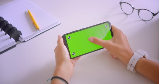 Closeup portrét mladých kavkazských businessů ruka držící telefon se zelenou clmou klíčem v kanceláři doma u stolu — Stock video