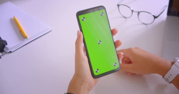 Крупним планом портрет кавказьких бізнесменів рука за допомогою телефону з зеленим екраном ключа хроми в офісі в приміщенні за столом — стокове відео