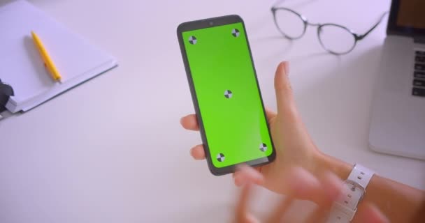 Närbild porträtt av businesswomans hand med hjälp av telefon med grön Chroma Key Screen i Office vid skrivbord inomhus — Stockvideo