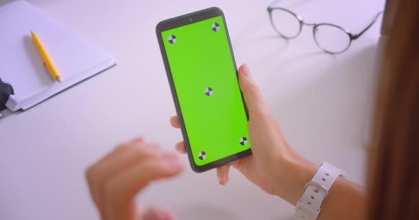 Close-up portret van zaken dames hand met behulp van telefoon met groene Chroma toetsen scherm met advt in kantoor op Bureau binnenshuis — Stockvideo