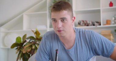 Apartmanın iç mekanlarında kanepede oturan uzaktan kumandayı tutarak Tv'de spor u izleyen yetişkin çekici beyaz adamın yakın çekim portresi