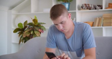 Telefon kullanarak ve kanepede kapalı oturan kameraya mavi renk ekran gösteren yetişkin çekici kafkas adam Closeup portre