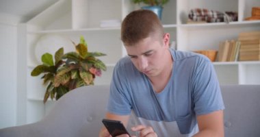 Telefon kullanarak ve kanepede kapalı oturan kameraya mavi renk anahtar ekranı gösteren yetişkin çekici kafkas adam Closeup portre