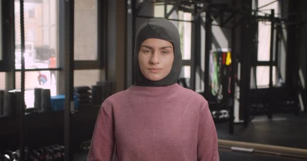 特写肖像年轻有吸引力的运动穆斯林女性看着相机与她的手臂交叉胸部在健身房在室内 — 图库视频影像