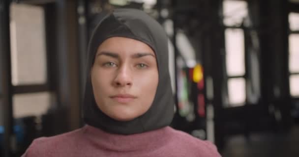 Closeup portrait of young attractive athletic muslim female looking at camera with motivation standing in gym indoors — Stock Video