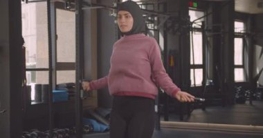 Kapalı spor salonunda türban atlama ip genç çekici atletik Müslüman kadın Closeup portre