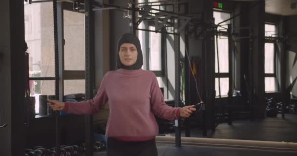Nahaufnahme Porträt junger attraktiver muslimischer Athletinnen beim Seilspringen in Turnhallen — Stockvideo