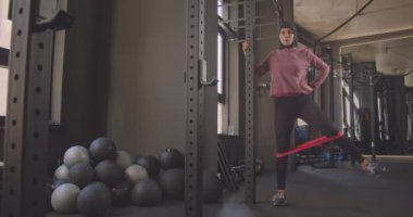 Bantüre genç çekici atletik Müslüman kadın kapalı spor salonunda bacak direnci eğitimi yapıyor Closeup portre