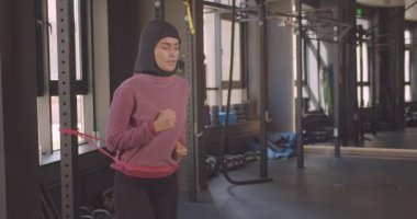 Hijab jogging genç çekici atletik müslüman kadın closeup portre kapalı spor salonunda direnç eğitimi yapıyor