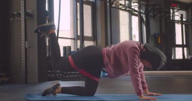 Türbanlı genç kararlı atletik müslüman kadın closeup portre kapalı bacak kaldırma direnç eğitimi yapma
