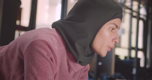 Closeup portrait of young determined athletic muslim female in hijab working out in gym indoors — Stock Video