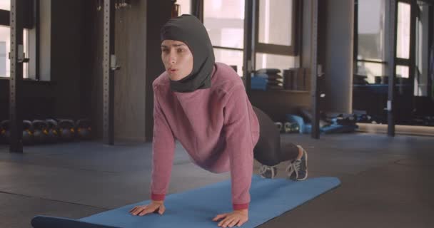 Gros plan portrait de jeune femme musulmane athlétique déterminée en hijab faisant de l'exercice de planche travaillant dans la salle de gym à l'intérieur — Video