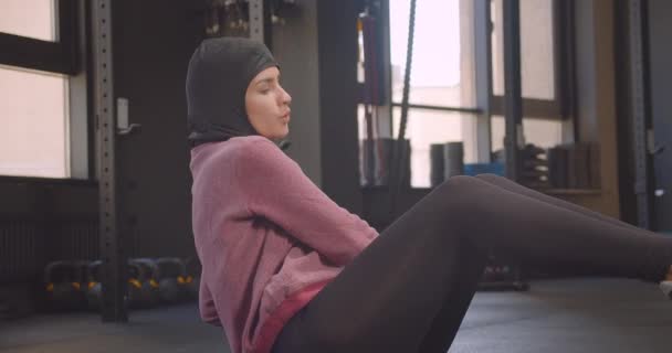 Close-up portret van jonge vastbesloten atletische Arabische vrouw in hijab trainen met bal in de sportschool binnenshuis — Stockvideo