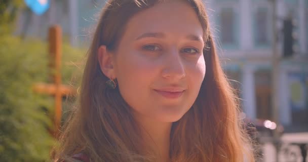 Close-up portret van jonge schattige blanke vrouw kijken naar camera lachen gelukkig in stedelijke stad buitenshuis — Stockvideo