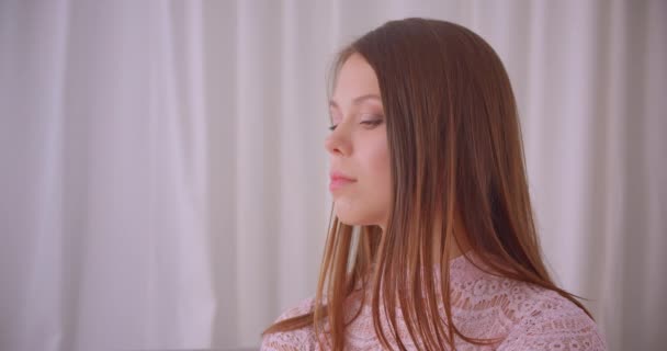 Closeup portrait of young attractive caucasian female looking at camera smiling cheerfully indoors in apartment — Stock Video