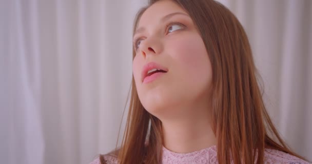 Closeup portrait of young cute caucasian girl looking at camera smiling happily indoors in cozy apartment — Stock Video