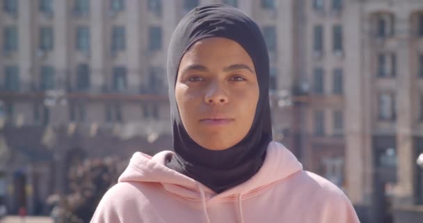 Gros plan portrait de jeune fille musulmane afro-américaine attrayante regardant la caméra dans la ville urbaine en plein air — Video