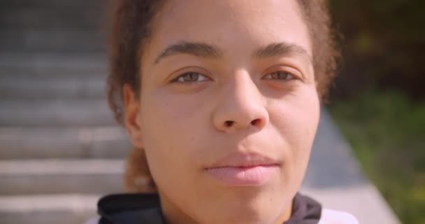 Closeup portréja fiatal vonzó afro-amerikai lány nézi kamera mosolygós boldogan városi város szabadban — Stock videók