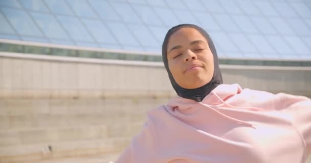 Close-up portret van jonge vrolijke Afro-Amerikaanse moslim meisje in hijab warming-up op stadion stedelijke stad buitenshuis — Stockvideo