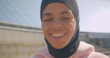 Hijab genç çekici Afrikalı Amerikalı Müslüman kız Closeup portre şehir şehir açık havada stadyumda mutlu bir şekilde gülümseyen kameraya bakarak