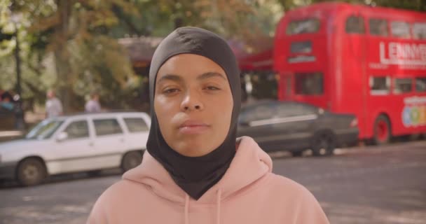特写画的年轻有吸引力的非洲裔美国穆斯林大学女孩在头巾微笑和笑愉快地站在城市街头户外 — 图库视频影像