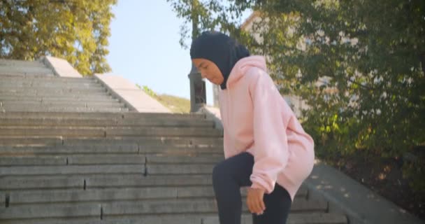 Closeup portrait of young attractive african american muslim girl in hijab doing lunges on stairs in urban city outdoors — Stock Video