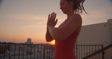 Arka planda güzel şehir manzara ile çatı üzerinde neşeyle gülümseyerek yoga pratik dreadlocks ile manevi kadın Closeup yan görünümü portresi