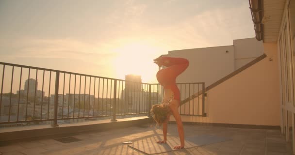 Closeup portrait of young athletic female with dreadlocks practicing yoga asanas on rooftop in city with beautiful sunrise on background — Stock Video