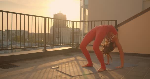Portret de aproape de sex feminin potrivit cu dreadlocks practica yoga asane pe acoperiș în oraș, cu răsărit frumos pe fundal — Videoclip de stoc
