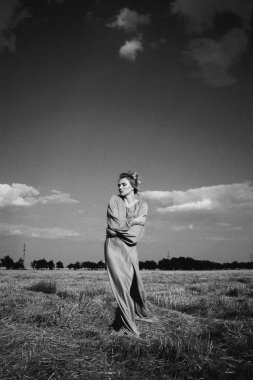 Harika bacakları, uzun elbisesi ve mavi gökyüzü arka planında harika bir kız. Köylü kızı. Turuncu elbiseli tutkulu kadın.