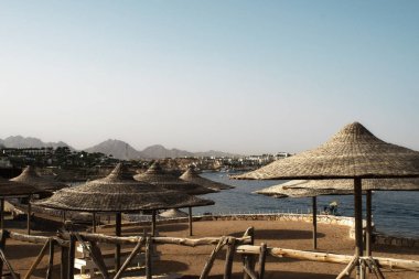 Egzotik ülkelerde tatil. Gök mavisi denizin arka planında ahşap şemsiyeler.