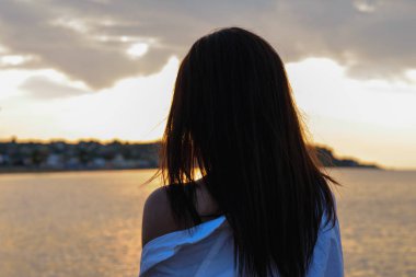 Çekici esmer, güzel gün batımına, rıhtımda şafağa hayran.