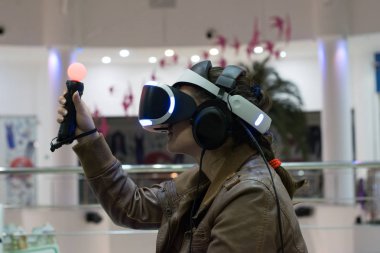 VR kulaklıklı, oyundan hoşlanan bir kız. Sanal gerçeklik. Oyun kumandalı VR kulaklıklı bir genç.