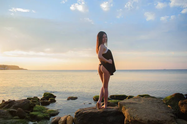 Bikini giymiş güzel bir kız deniz ve gün batımına karşı, şafak vakti.